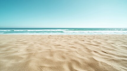Obraz premium A wide expanse of sandy beach leads to a vibrant ocean under a vast blue sky, offering an inviting space that overflows with tranquility and boundless possibilities.