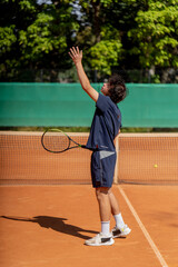 professional tennis court young curly guy technically performs the first serve in the game examines it clay court markings