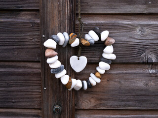 Heart Stones - Close-up of white and gray heart-shaped stone clinging to wooden panels in the background