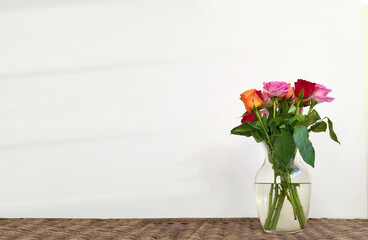 Obraz premium Elegant bouquet of pink roses in a glass vase on a wooden table for romantic celebration or interior decoration.