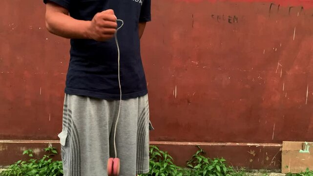 4K video of male hand playing yoyo. A yoyo is a toy consisting of two disks connected by an axle around which a string is wound. A yoyo is thrown down on a string and can be returned to the hand