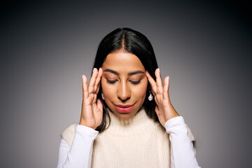 The beautiful woman appears introspective, lightly touching her temples in a serene moment.