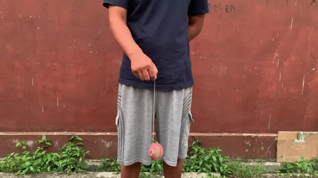 4K video of male hand playing yoyo. A yoyo is a toy consisting of two disks connected by an axle around which a string is wound. A yoyo is thrown down on a string and can be returned to the hand