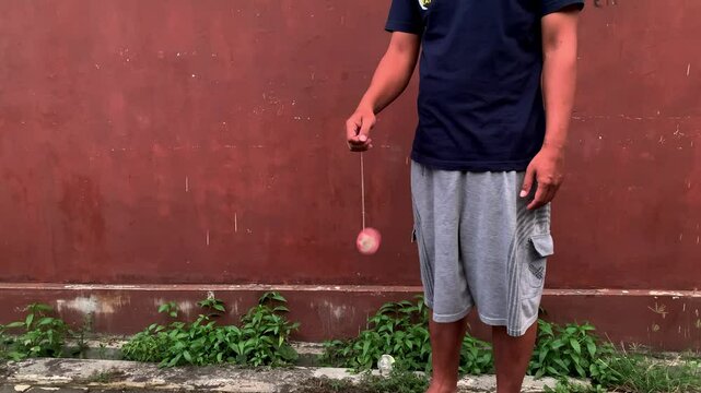 4K video of male hand playing yoyo. A yoyo is a toy consisting of two disks connected by an axle around which a string is wound. A yoyo is thrown down on a string and can be returned to the hand