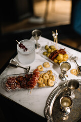 cocktails, silver shot glasses, apptitzers (tarallini, salami, olives) on the marble table at the bar