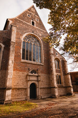 An old Gothic-style church in an autumn landscape. The church’s tall spires and pointed arches...