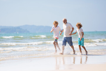 Naklejka premium Grandfather and kids on summer beach