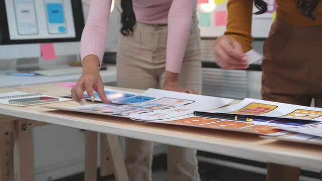 Designers discussing mobile application design while collaborating on a flowchart for user experience planning