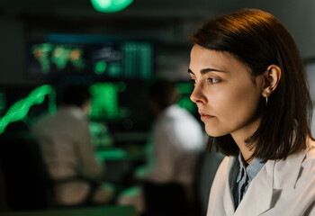 Focused medical researcher analyzing data on computer screens in a high-tech laboratory, contributing to scientific advancements