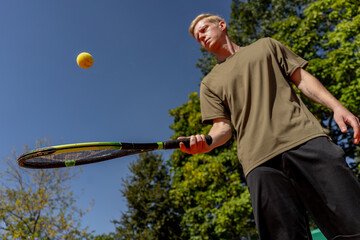low shot professional tennis court young curly guy trains hitting the ball with tennis racket professional preparation for the game