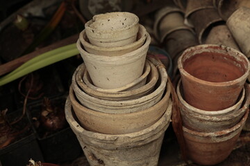 Closeup of stacks of old used terra cotta flower pots in gardening shed