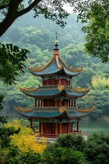 Fototapeta premium A traditional Chinese pagoda stands beside lush greenery over a serene body of water, surrounded by a tranquil forest.