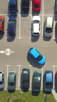 AERIAL TOP DOWN: Flying above female bad driver incapable to park a car on parking space in crowded parking lot. Woman having problems, unable to park a car in parking spot. Parking fail on parkspace