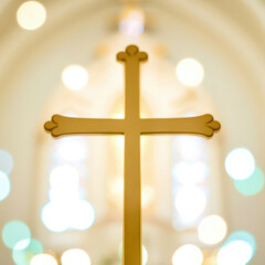 A gold cross is shown in a church with a blurry background