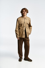 Fototapeta premium A handsome young man with wavy hair showcases a trendy autumn look in a sleek studio setting.