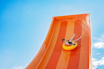 Young boy playing in outdoor aqua park. Teenager having fun with sliding on inflatable rubber...