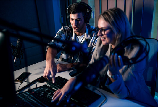 Young woman and man editing audio podcast in their studio.