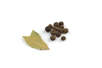 two dried bay leaves and allspice on a white background.