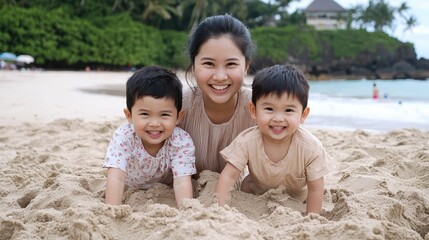 A happy mother poses on the beach with her two smiling children, playing in the sand surrounded by greenery and a serene ocean backdrop.