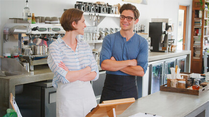 Obraz premium Smiling Male And Female Owners Or Workers Behind Counter In Coffee Shop