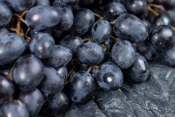 fresh grapes are lying on black paper