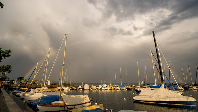 Rainbows and moored sailboats by lake in Morges, Switzerland