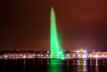 Illuminated green fountain over Lake Geneva at night
