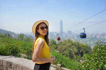 Fashion tourist woman on terrace in Santiago Metropolitan Park with cable cars and cityscape of...
