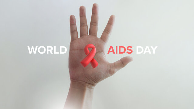A hand displays a red ribbon symbolizing awareness for World AIDS Day, highlighting the global fight against HIV/AIDS.