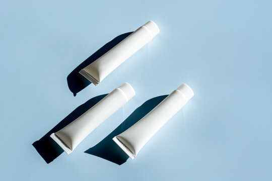 Top view of three luxury skincare tubes on blue background