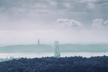 Panoramic view of 25 de abril bridge and cristo rei statue in lisbon, portugal, under a cloudy sky,...