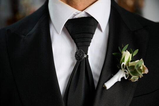 Close-up of groom's attire with tie and boutonniere at wedding