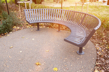 Stylish curved metal bench in a landscaped park setting, blending contemporary design with natural...