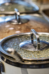Fototapeta premium buffet serving station, ceramic non stick saucepan pot with glass lids warming the food