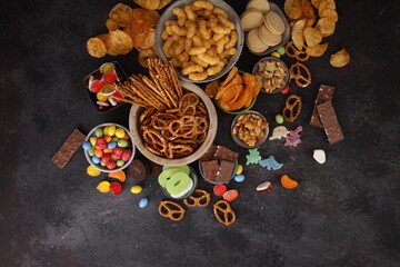 Salty and sweet snacks. Pretzels, chips, crackers, popcorn in wooden bowls on table
