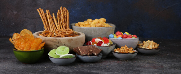 Salty and sweet snacks. Pretzels, chips, crackers, popcorn in wooden bowls on table