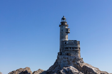 Aniva - The abandoned lighthouse in the Sakhalin Island, Korsakov district, Russia. Pacific ocean. The abandoned lighthouse Island Blue sea. Beautiful view. Blue sky and blue Pacific ocean.