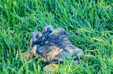 Aged sport sneakers on grassy field, well-used shoes in nature