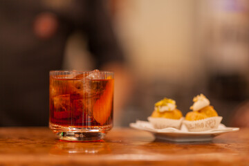 Close up on americano cocktail appetizer on a bartender table, background is blurred.