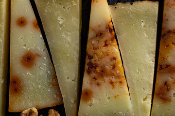 Un triángulo de queso curado capturado en primerísimo plano, mostrando su textura firme y su...
