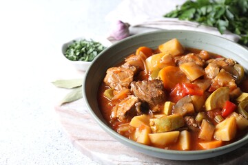 Delicious stew with vegetables in bowl and spices on table, closeup