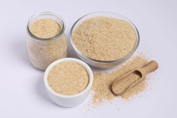 Oat bran in bowls, glass jar and wooden scoop on white background