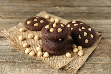 Tasty chocolate cookies with hazelnuts on wooden table, closeup