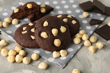 Tasty chocolate cookies with hazelnuts on grey table, closeup