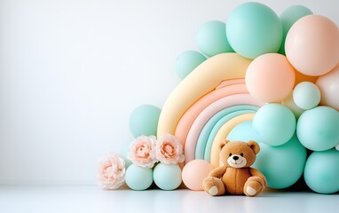 Obraz premium A colorful arrangement of pastel balloons forms a playful rainbow backdrop, accompanied by a cute teddy bear and soft floral elements.