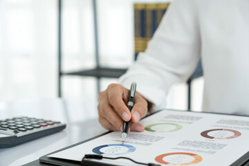 Businesswoman working in office analyzing charts and graphs.