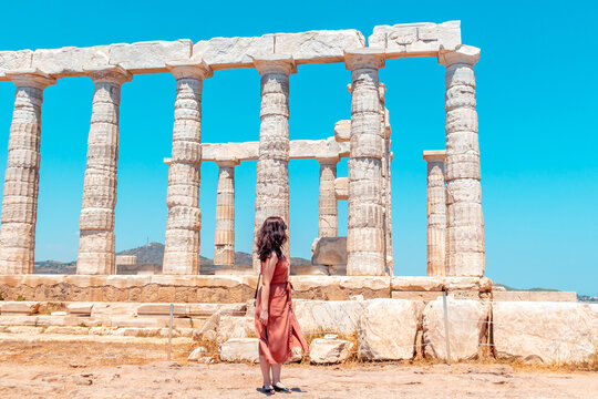 A young girl walks around ancient temple of Poseidon on the Cape Sounion during a long-awaited summer vacation in Greece