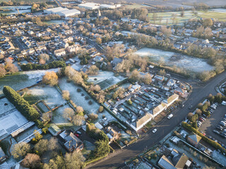 Obraz premium Aerial view of old and new houses seen on a frosty morning in Cambridgeshire, UK. Large, snow covered gardens are visible.