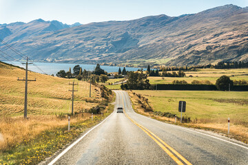 Road trip car driving on the road in autumn forest at New Zealand