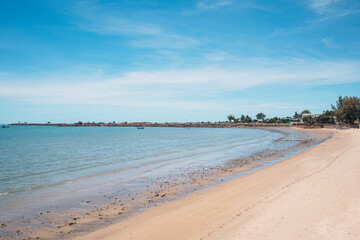 Fototapeta premium Tropical sea beach with fishing boat by stone jetty in summer